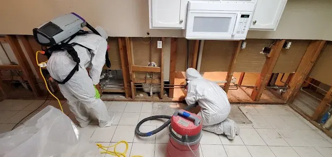 Workers in protective clothing cleaning an opened wall cavity